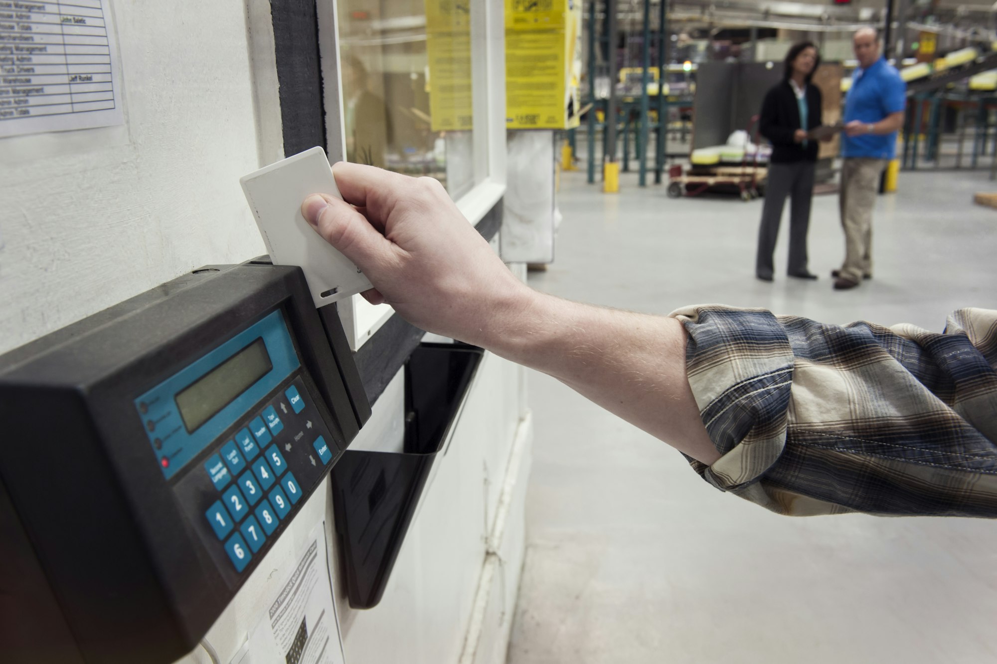 person clocking in at a factory time clock card