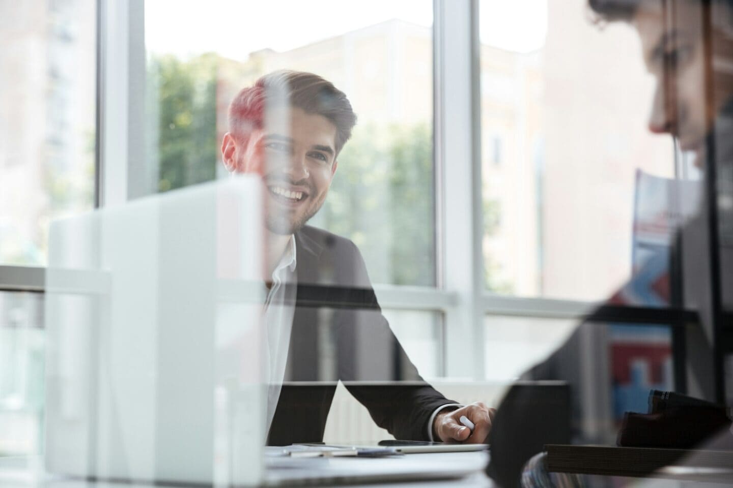 Two cheerful young businessmen with laptop on business meeting